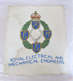 An embroidered rectangle of cream fabric, with coloured REME first cap badge and words ROYAL ELECTRICAL AND MECHANICAL ENGINEERS.